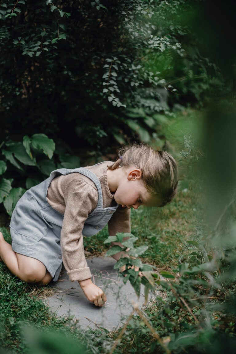 Petite fille dans la nature écrit avec une craie sur un carreau en ardoise au sol